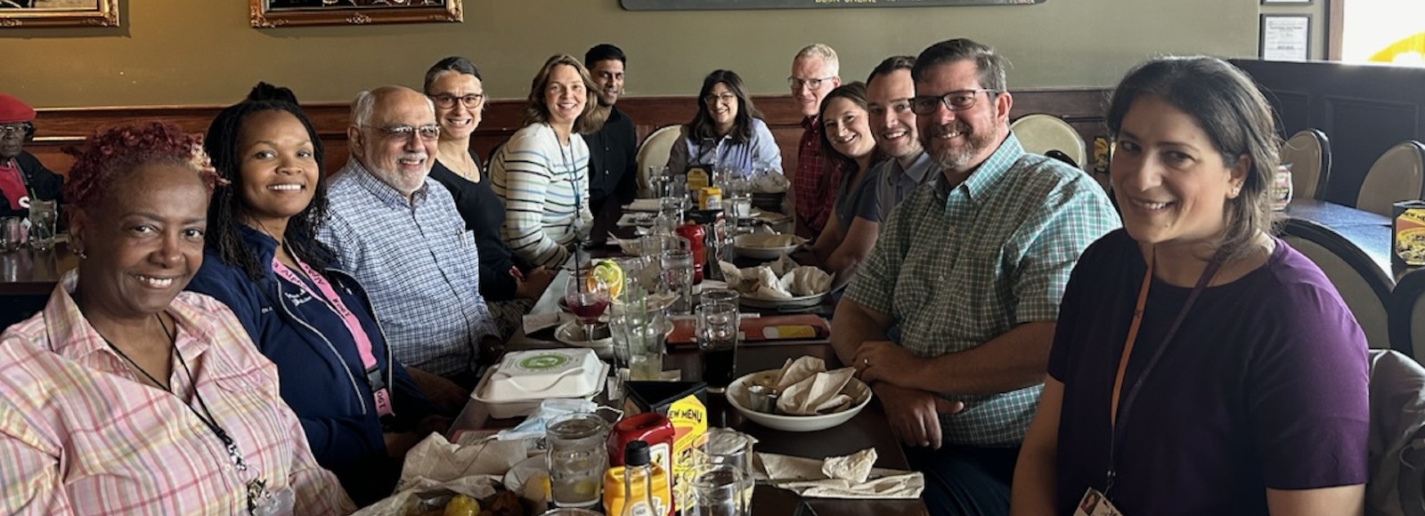 group of males and females sitting and smiling at a table